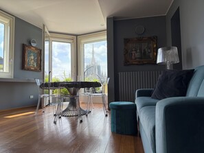 A room with a dining table, chairs, a sofa, and a radiator.
