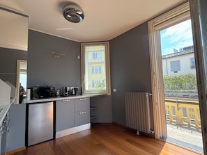 Eine moderne Küche mit grauen Schränken, einer eingebauten Mikrowelle und einem Fenster mit Blick auf einen Balkon.