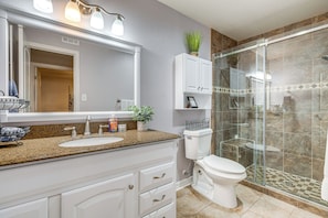 A bathroom with a granite countertop, white cabinets, a toilet, and a glass-enclosed shower. - On Golf Course! Resort-Style Lago Vista Retreat (Lago Vista)
