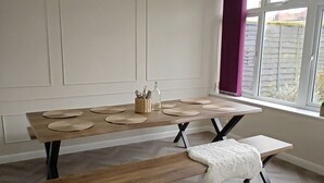 Eine moderne Küche mit Holztisch und Bank, weißen Schränken und einem Fenster mit Blick.