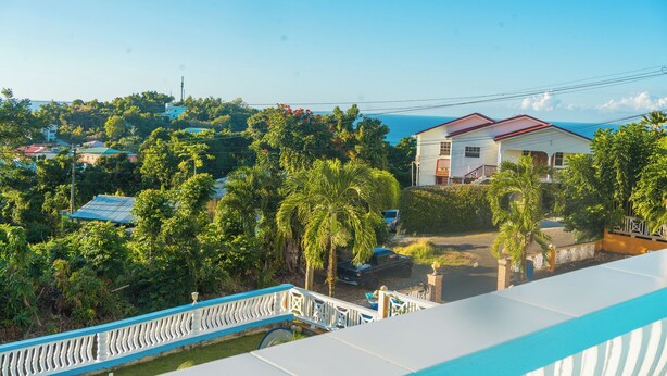 A residential area with a house surrounded by lush greenery and a clear view of the sea. - SK Safe Haven #1 (Castries)