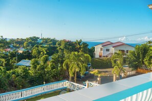 A residential area with a house surrounded by lush greenery and a clear view of the sea. - SK Safe Haven #1 (Castries)