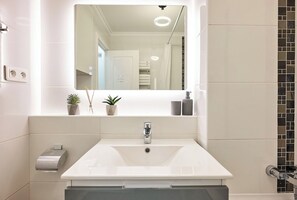 A bathroom with a white sink, a mirror, and a towel rack.