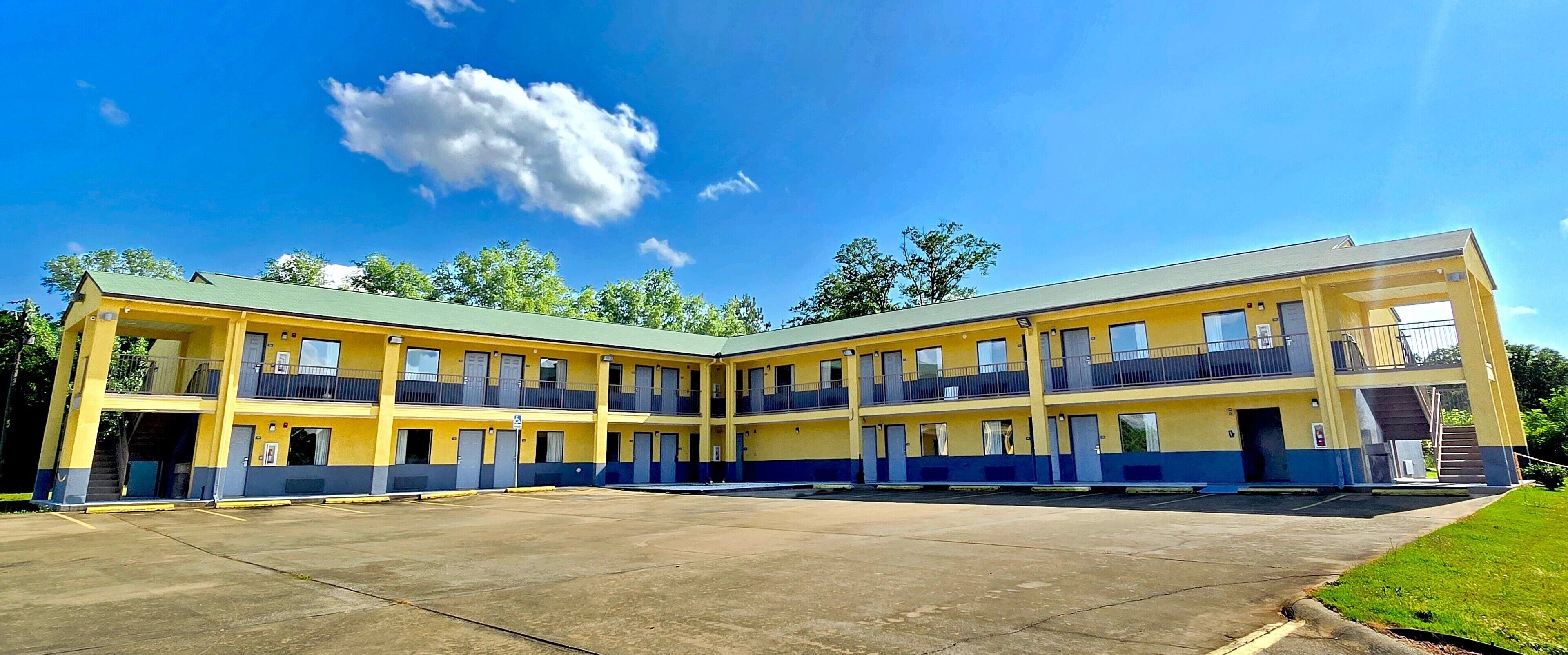 Un motel de varios pisos con un patio central, que cuenta con balcones y una escalera para acceder a los niveles superiores.