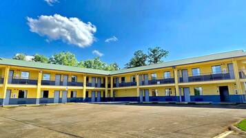 Un motel de varios pisos con un patio central, que cuenta con balcones y una escalera para acceder a los niveles superiores.
