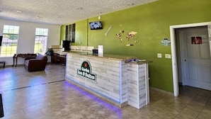 Un comptoir d’accueil avec une enseigne indiquant « Garden Inn & Suites », un téléviseur fixé au mur et une carte du monde.