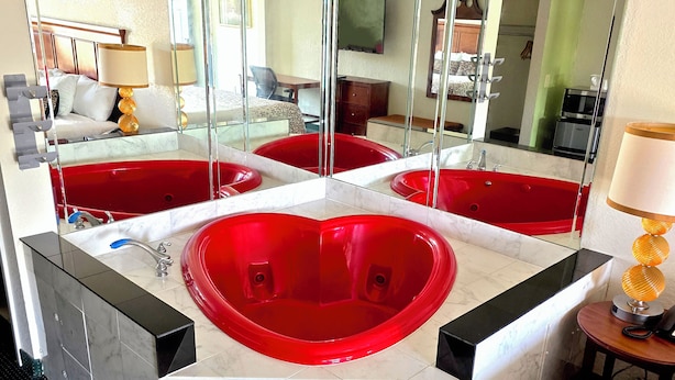 Une salle de bain avec une grande baignoire rouge, un miroir et un lavabo.