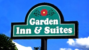 Une enseigne pour le Garden Inn & Suites, avec un fond vert et des lettres blanches.