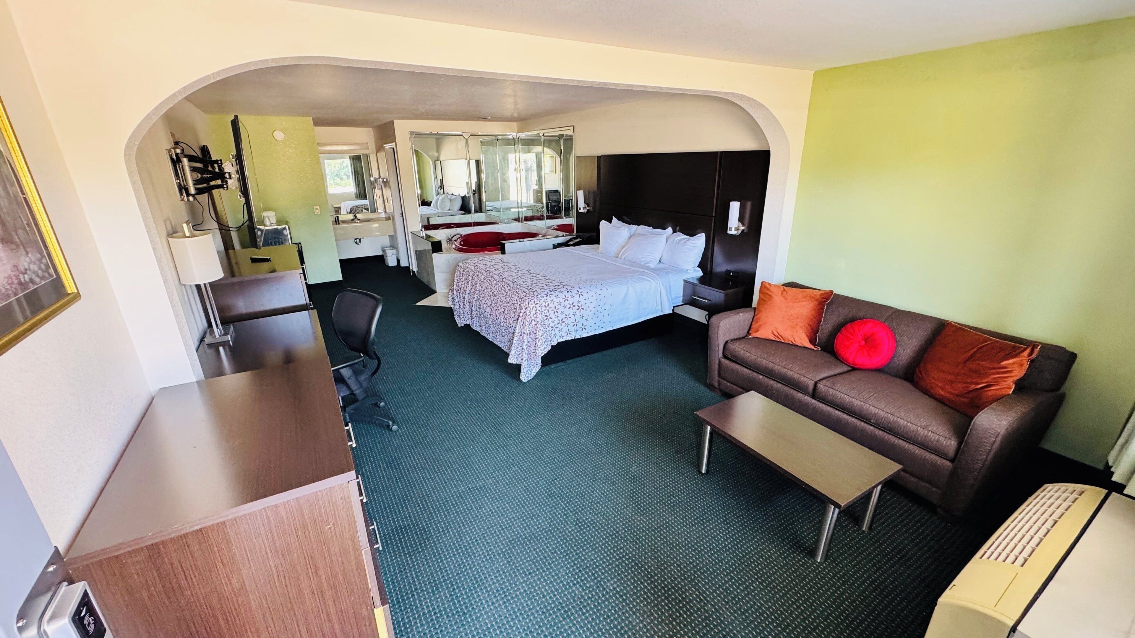 Une chambre d’hôtel avec un lit, un canapé, un bureau et un miroir.