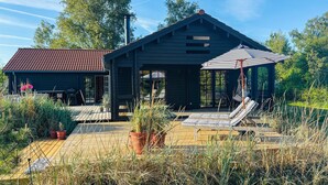 Een modern huis met een terras, zitplaatsen buiten en een grote parasol.