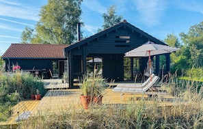 Une maison moderne dotée d’un patio, d’un espace salon extérieur et d’un grand parasol.