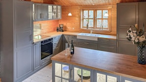 Een moderne keuken met grijze kastjes, een houten aanrechtblad en een groot raam.