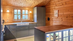 Een moderne keuken met houten wanden, een groot raam en een inbouwkast met glazen deuren.