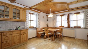 A kitchen with wooden cabinets, a dining table with chairs, and a window with curtains.
