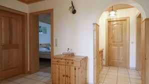 A hallway with wooden doors, a tiled floor, and a small wooden cabinet with drawers.