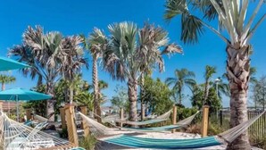 Un hamac installé sur une plage de sable, avec des palmiers en arrière-plan.