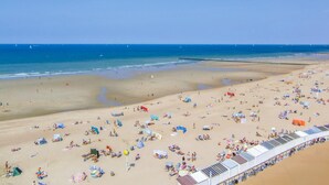 A beach with numerous sunbeds and umbrellas, a clear sky, and calm sea.