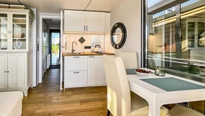A compact kitchen with white cabinetry, a sink, and a dining area with a table and chairs. - Stunning ship in Ophoven with WiFi (Ophoven)