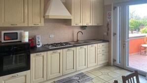 A kitchen with wooden cabinets, a gas stove, a microwave, and a sink. - 1 bedroom amazing apartment in Pompei (Pompei)