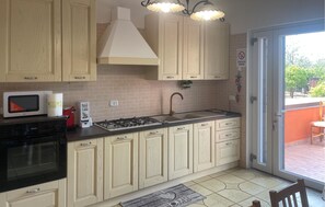 A kitchen with wooden cabinets, a gas stove, a microwave, and a sink. - 1 bedroom amazing apartment in Pompei (Pompei)