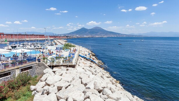 A coastal area with a rocky shoreline, a marina with boats, and a distant mountain. - 1 bedroom amazing apartment in Pompei (Pompei)