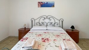 A bed with a floral bedspread, two nightstands with lamps, and a painting of a coastal scene on the wall. - 1 bedroom amazing apartment in Pompei (Pompei)