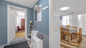 A modern kitchen with a dining area, a red chair, and a 'Welcome' sign on the wall.