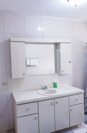 Une salle de bain avec un meuble-lavabo blanc, un miroir et un évier.