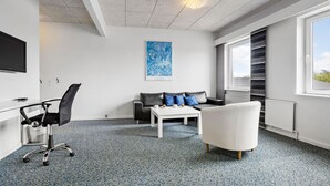 A modern office space with a white desk, black office chair, white sofa, and a white armchair. There is a large window with a view of the sky and a blue abstract painting on the wall. - 11 bedroom gorgeous home in Hurup Thy (Hurup Thy)
