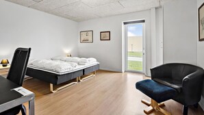 A modern hotel room with a bed, a desk, a chair, and a door leading to a balcony. - 11 bedroom gorgeous home in Hurup Thy (Hurup Thy)