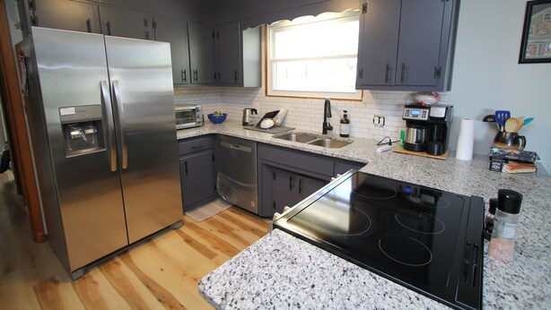 A modern kitchen with stainless steel appliances, granite countertops, and dark gray cabinetry. - The Maine House in State College - 2 miles to PSU via walking path or car! (State College)