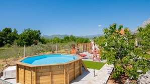 A wooden hot tub with a pool, surrounded by a patio area with a swing set and a small deck. - Beautiful home in Zavojane (Zavojane)
