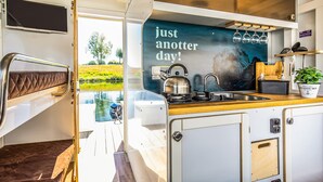 A compact kitchen with a view of a lake, a kettle, and a sign saying "just another day!". - Lovely ship in Ophoven with lake view (Ophoven)