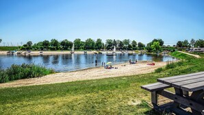 A lakeside park with picnic tables, boats, and a sandy beach. - Lovely ship in Ophoven with lake view (Ophoven)