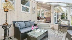 Un espace de vie extérieur accueillant, avec un canapé, une table basse et des fauteuils en osier.