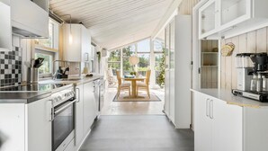 Une cuisine moderne avec des meubles blancs, des appareils en acier inoxydable et un coin repas comprenant une table et des chaises en bois.