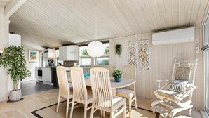 Une cuisine moderne avec des meubles blancs, un coin repas avec des chaises en bois et une grande fenêtre qui laisse entrer la lumière naturelle.
