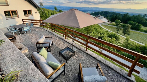 Un patio con mobiliario exterior, una mesa y una sombrilla grande.
