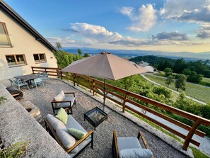 Eine Terrasse mit Gartenmöbeln, einem Tisch und einem großen Sonnenschirm.