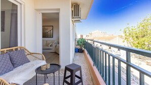 A balcony with a wicker sofa, a small table, and a potted plant. - Stunning apartment in El Campello with WiFi (El Campello)