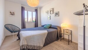 A bedroom with a bed, a chair, a lamp, and a window. - Stunning apartment in El Campello with WiFi (El Campello)