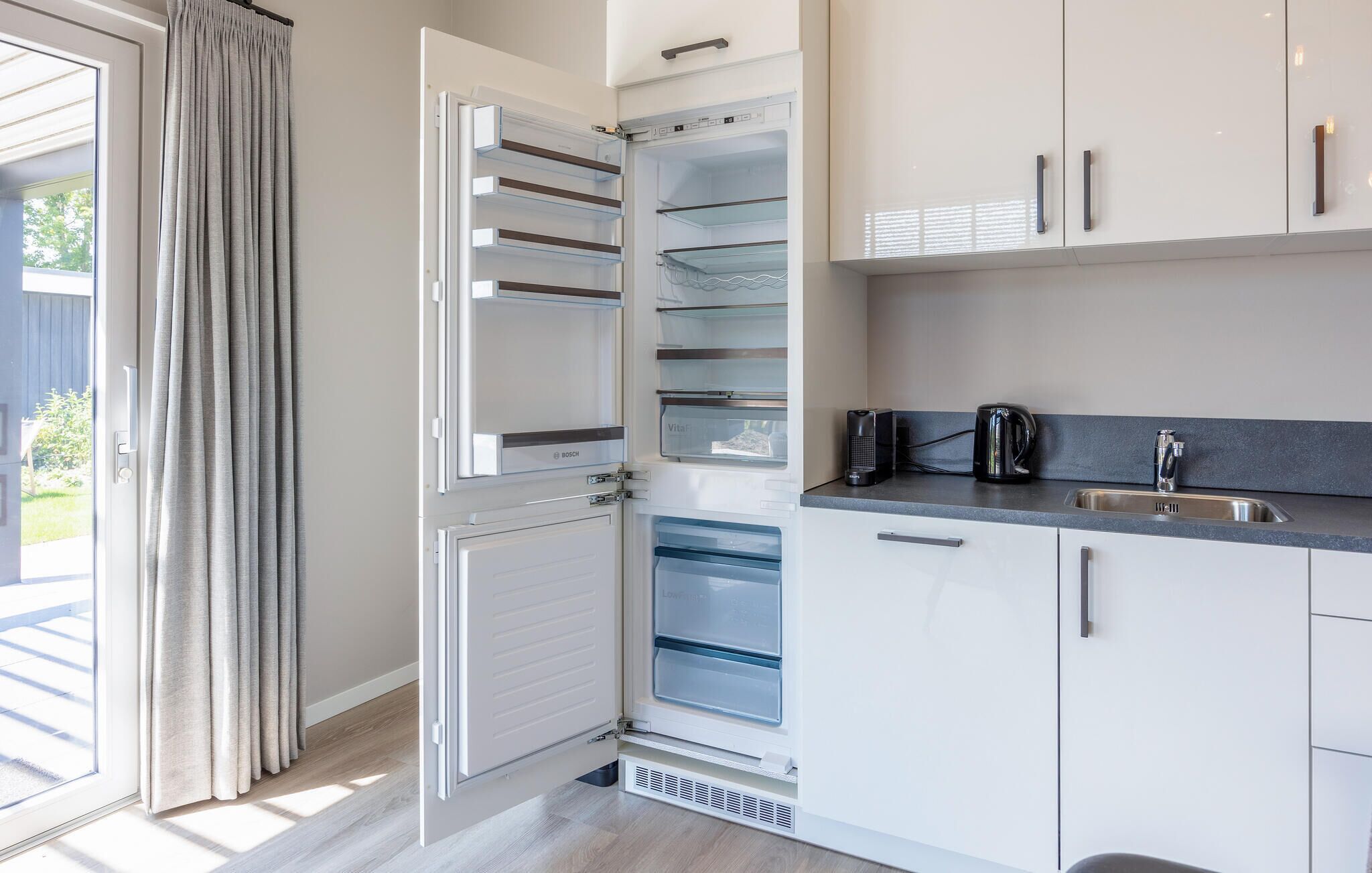 Une cuisine moderne avec des armoires blanches, un comptoir noir et un lave-vaisselle encastré.