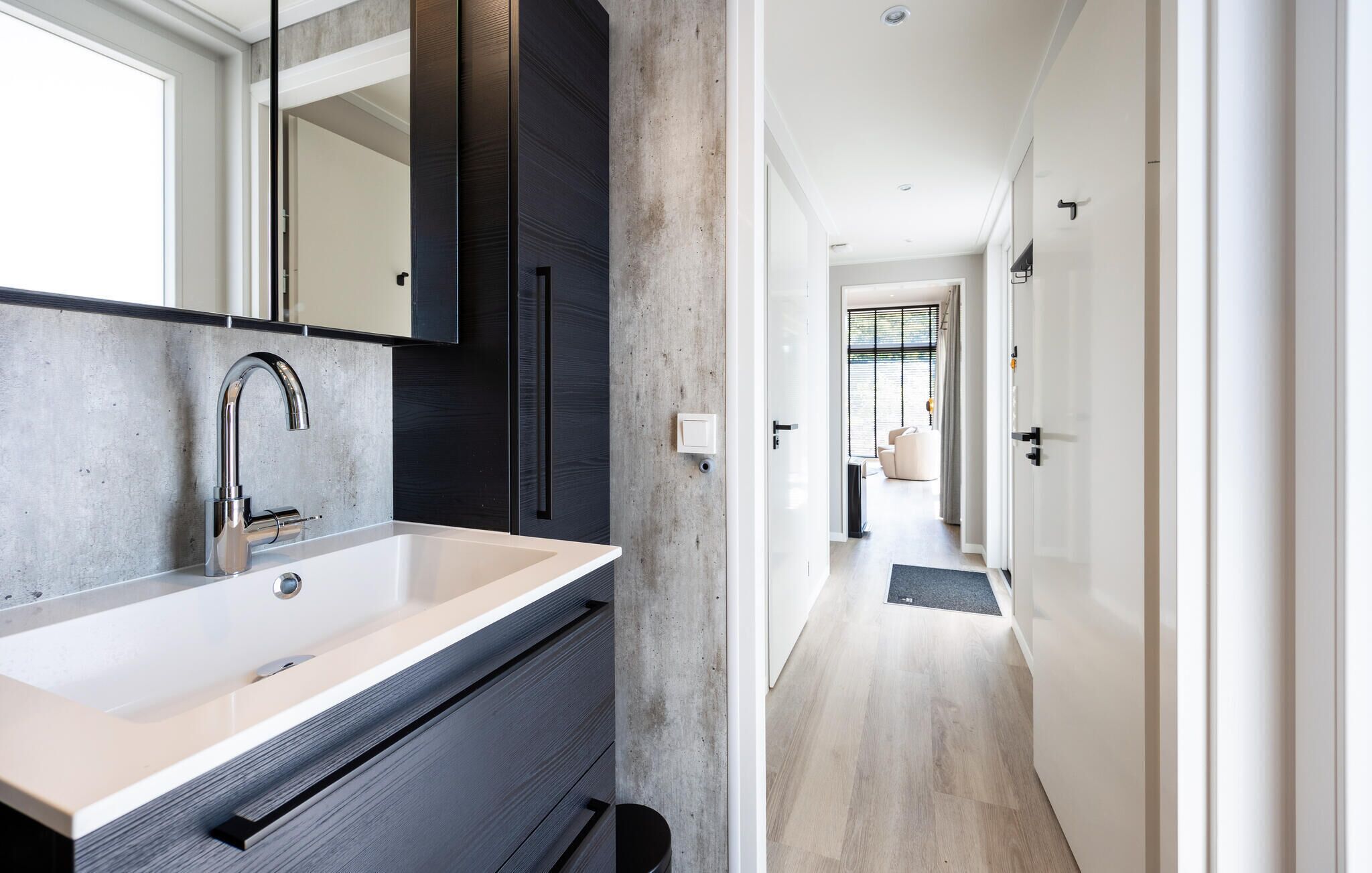 Un baño moderno con un lavamanos grande, un espejo y un mueble oscuro.
