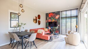 Ein modernes Wohnzimmer mit Essbereich, einem roten Sofa und einem an der Wand montierten Fernseher.