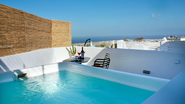 A rooftop infinity pool with a view of the sea, a small table with a bottle, and a chair. - Wine Cellar House | Exclusive retreat that redefines luxury living in Santorini (Thira)