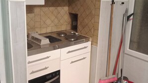 Une cuisine compacte équipée d’une cuisinière, d’un four et de meubles blancs.