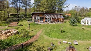 A cabin with a deck, surrounded by a grassy area and trees.