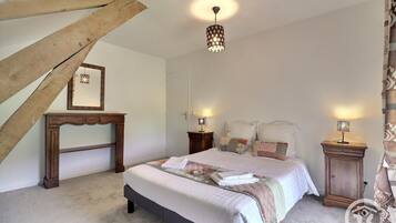 Una camera da letto con un letto, comodini, una lampada a sospensione e travi in legno a vista.