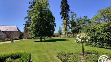 Un jardín bien cuidado con diferentes árboles, césped y parterres de flores.