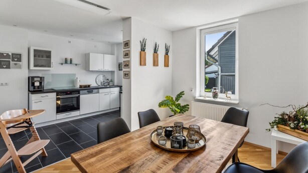 A modern kitchen with white cabinets, a dining table with candles, and a view of the outside. - Cozy apartment in Bad Harzburg with WiFi (Bad Harzburg)